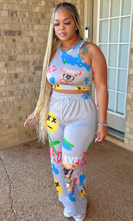 Woman wearing the That Cool Girl Set featuring a gray sleeveless crop top and matching high-waisted wide-leg pants with colorful graffiti-inspired graphics, front view.