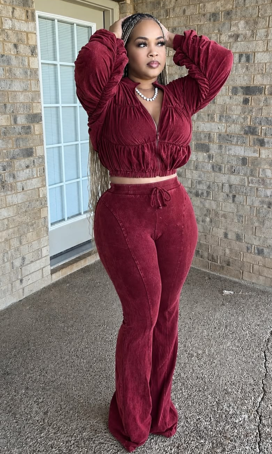 The model is wearing the Weekend Ruched Set Red showing ruched detailing across the cropped jacket, gathered sleeves, elasticized hem, and matching high-waisted flared pants.