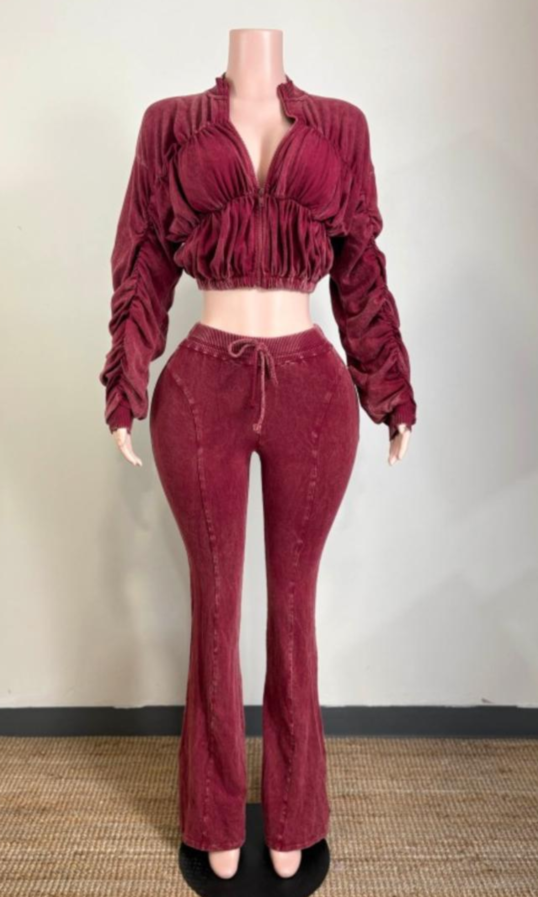 Burgundy red acid-wash two-piece matching set featuring a cropped zip-front jacket with dramatic ruching, gathered long sleeves, and high-waisted drawstring flared pants displayed on a