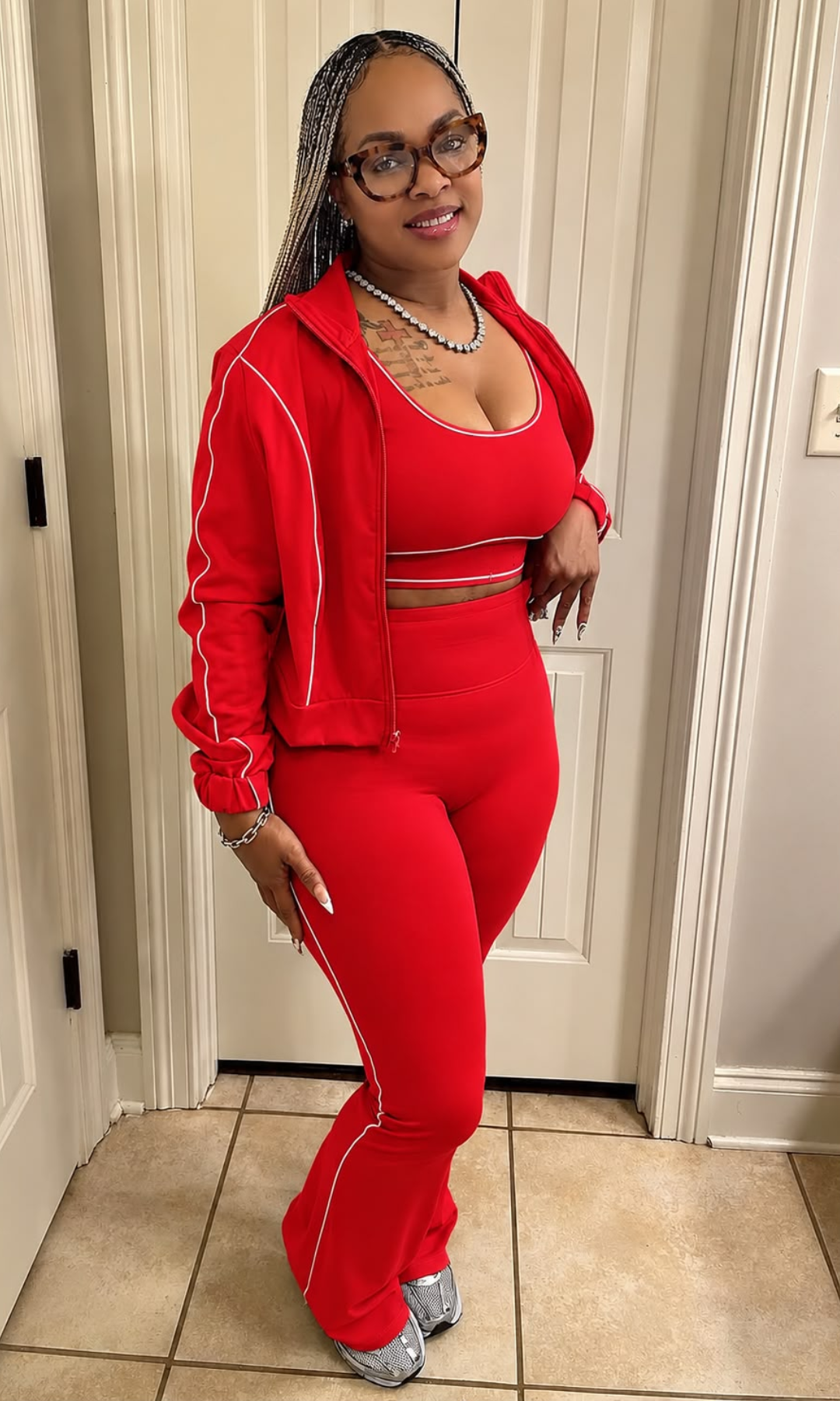 Model wearing the Tutu Set Red, a vibrant red three-piece matching outfit featuring a scoop-neck crop top, zip-up jacket with white piping, and high-waisted flared pants.