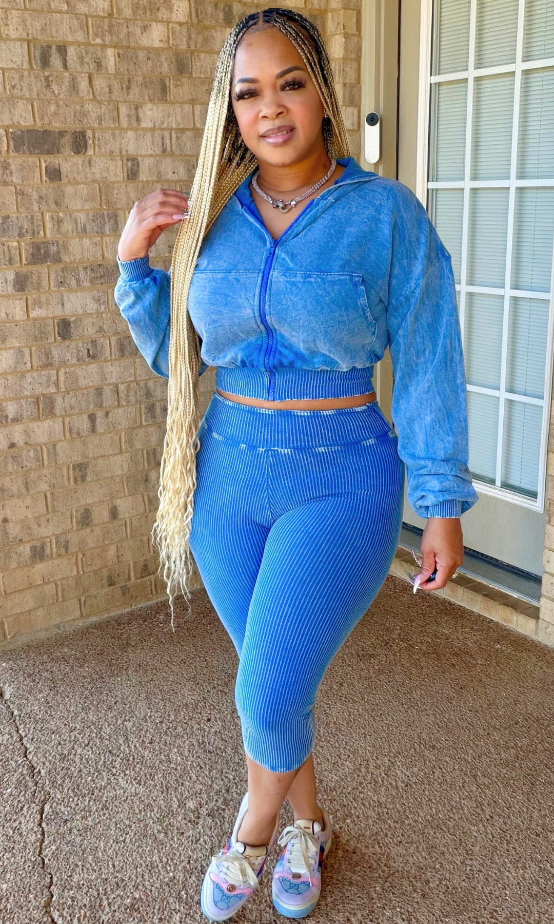 Woman wearing the Uptown Edge Blue Short Set featuring a washed blue cropped zip-up hoodie and matching high-waisted ribbed capri bottoms, front view.